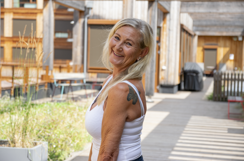 Marianne står smilende i sansehagen på Oksenøya sykehjem
