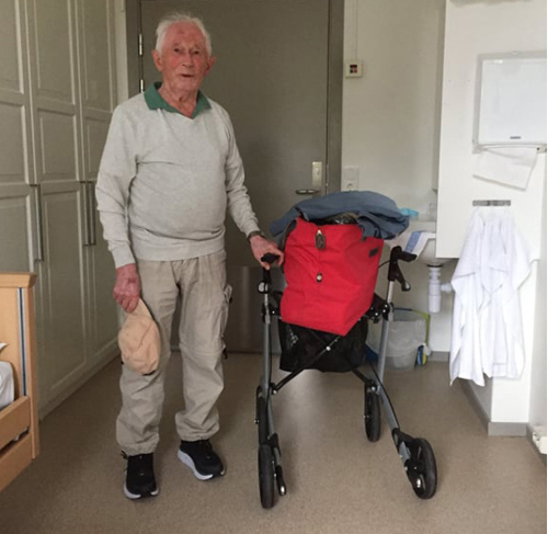 Bilde av Invart på rommet sitt. Han har pakket sin bag og bruker gåstolen som tralle for bagen
