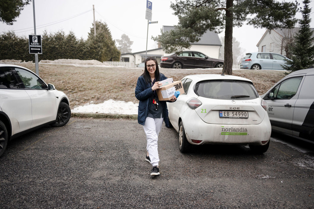 Miruna går fra bilen og inn til en bruker med en eske med utstyr